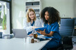© NanSan - An African American female doctor and a white female doctor work at  hospital desk, discussing patient treatment,medical analysis,healthcare strategies ensure quality medicine effective patient care