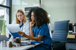© NanSan - An African American female doctor and a white female doctor work at  hospital desk, discussing patient treatment,medical analysis,healthcare strategies ensure quality medicine effective patient care