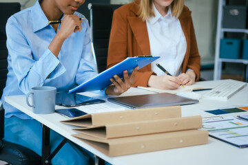 Wall Mural - An African American businesswoman and a Caucasian woman work at analyzing market data, developing business strategies,discussing financial growth while using a laptop spreading money for investment