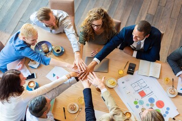 Poster - Diverse team in a meeting room, hands together in unity. Business meeting with teamwork, collaboration, and unity. Office setting with diverse professionals. Business people in teamwork stacking hands