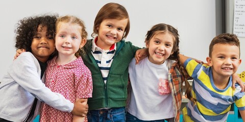 Poster - Diverse group of happy children smiling, hugging, and posing together in a classroom. Kids, friendship, and joy are captured in classroom. Happy kids embrace in front of whiteboard in classroom.