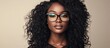 © StockKing - Confident young black woman with curly hair wearing stylish glasses on a neutral background, showcasing elegance and fashionable confidence.