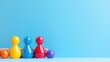 © BROPRADANA - Colorful wooden game pawns and spheres arranged in a row by human hands against a blue background.