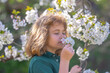 © Volodymyr - Little kid smelling spring flower outdoor. Portrait of smiling child face near blossom spring flowers. Kid among branches of spring tree in blossoms. Cute kids face surrounded by spring blossom