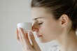 © Fotograf - A woman holds a cup of creamy liquid to her nose, enjoying the aroma