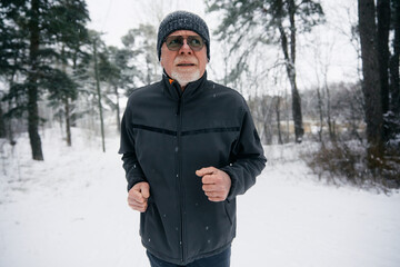 Wall Mural - Senior Man Jogging Through a Snowy Forest