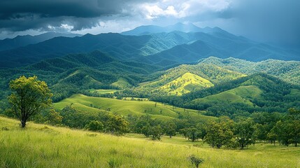 Wall Mural - Scenic view of rolling green hills and distant mountains under dramatic sky.