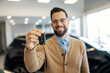 © Dusan Petkovic - Close up of a car buyer showing keys of his brand new car at car showroom.
