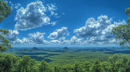 Wall Mural - View of green forest and hills under a blue sky with clouds.