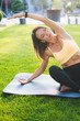 © Strelciuc - A woman is practicing yoga on a lush green grass area surrounded by a peaceful, serene setting