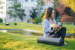 © Strelciuc - A woman is relaxing outdoors on her yoga mat while enjoying the use of her smartphone