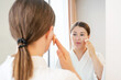 © TATIANA KIM - Young woman applying brown cushion on face with pad close-up front view.