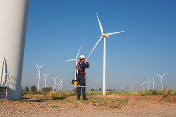 Wall Mural - engineer wearing uniform inspection and survey work in wind turbine farms rotation to generate elect