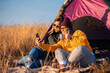 © Zoran Zeremski - Two women camping at top of the hill sitting in front of the tent making selfie.