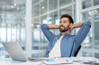 © Liubomir - Businessman well done successfully completed the project. Man in casual clothes with hands behind head is contentedly resting and relaxing at workplace with laptop, inside office.