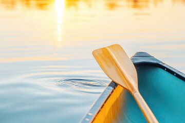 Poster - close-up of wooden canoe paddle dipping into calm lake tiny ripples spreading golden light reflectin