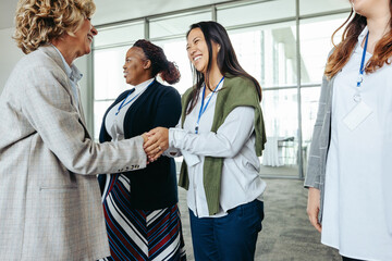 Wall Mural - female business professionals meeting and shaking hands at a corporate event