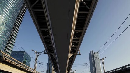 Poster - Elevated train track runs through urban landscape filled with modern skyscrapers during bright daylight