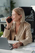 © TrueFrame Collective - Successful mature blond female boss speaking to client of company on mobile phone in front of laptop
