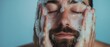 © felix_brönnimann - Man washing face with foam during skincare routine in bathroom, emphasizing self-care, hygiene, and grooming habits for improved skin health and appearance.