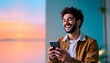 © DhanaStudio - Cheerful man using his smartphone with beautiful sunset background, expressing happiness and connection, perfect for social media, blog content, and advertising.