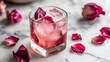 © Seyyar - Organic flower petal ice cubes in a cocktail glass with rose petals on a marble surface creating a refreshing and elegant drink presentation.