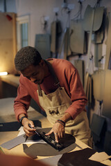 Aufkleber - Skilled craftsman in apron working in well-lit workshop, carefully measuring material for precise cuts, focusing on accuracy and detail