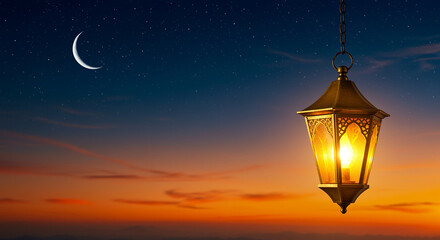 Poster - Lantern hanging in the night sky with crescent moon. City lantern with a warm glow against the twilight sky
