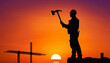 © Ali Ula - Construction worker silhouette holding an axe against sunset sky