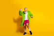 © deagreez - Eccentric senior man in vibrant outfit dancing against a yellow background in a playful and trendy expression of personal style and freedom