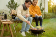 © tonefotografia - Couple Enjoys Grilling Outdoors in a Cozy Garden Setting During a Sunny Afternoon