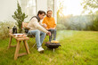 © tonefotografia - Couple Enjoys Grilling Outdoors in a Cozy Garden Setting During a Sunny Afternoon