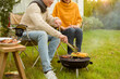 © tonefotografia - Couple Enjoys Grilling Outdoors in a Cozy Garden Setting During a Sunny Afternoon