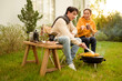© tonefotografia - Couple Enjoys Grilling Outdoors in a Cozy Garden Setting During a Sunny Afternoon