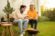 © tonefotografia - Couple Enjoys Grilling Outdoors in a Cozy Garden Setting During a Sunny Afternoon