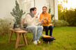 © tonefotografia - Couple Enjoys Grilling Outdoors in a Cozy Garden Setting During a Sunny Afternoon