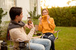 © tonefotografia - Couple Enjoys Grilling Outdoors in a Cozy Garden Setting During a Sunny Afternoon