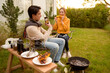 © tonefotografia - Couple Enjoys Grilling Outdoors in a Cozy Garden Setting During a Sunny Afternoon