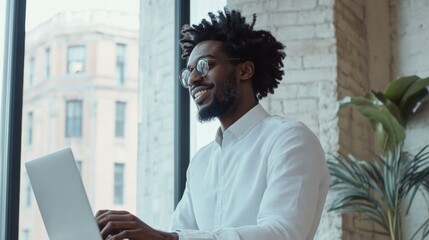 Leinwandbilder - Contemporary Professional Success Confident Businessman in Smart Casual Attire, Engages with Laptop in Minimalist OfficeIdeal for Modern Corporate Branding and Workplace Dynamics