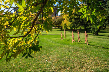 Wall Mural - A group of four sculptures of people walking in a park