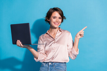 Poster - Smiling girl holding laptop and pointing against blue background conveying happiness and confidence