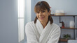 © Krakenimages.com - Young, beautiful, brunette, woman with short hair wearing a white bathrobe while smiling at a spa, salon, beauty center room with a wellness, relaxing indoor environment