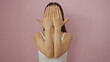 © Krakenimages.com - Woman covering her face with hands against a pink wall dressed in a white top with an isolated background.