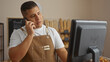 © Krakenimages.com - Young hispanic man working in a bakery talking on a phone while looking at a computer screen in an indoor setting
