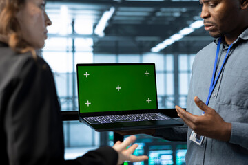 Poster - Teamworking coworkers in data center using automation tools on green screen mockup laptop. Engineers ensuring continuous uptime of server farm, managing data flows with chroma key device