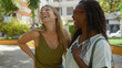 © Krakenimages.com - Women laughing together in a vibrant city park during a sunny day showcasing friendship and joy outdoors in an urban setting