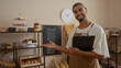 © Krakenimages.com - Young arab man with beard smiling in bakery shop interior presenting pastries and holding clipboard