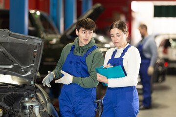 Wall Mural - Car service manager discusses car repair problems with a mechanic. He takes notes on paper