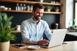 © velikiyzayats - Cheerful Young Adult Male Working Remotely on Laptop in Modern Home Kitchen, Surrounded by Indoor Plants and Natural Light, Embracing Productivity and Comfort