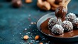 © Yuliia - Homemade chocolate coconut truffles with melted dark chocolate drizzle on plate against dark background, selective focus on dessert balls with almonds.